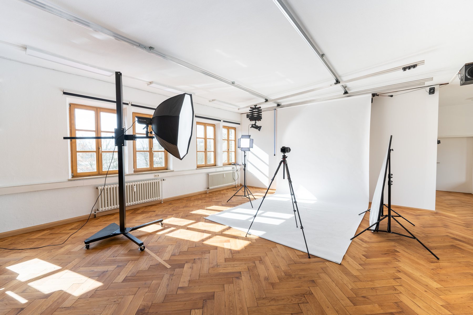 Helles Produktionsstudio von KINGUNION mit ausgerolltem Hintergrund, Dauerlicht, Kamera auf Stativ und Deckenschienensystem